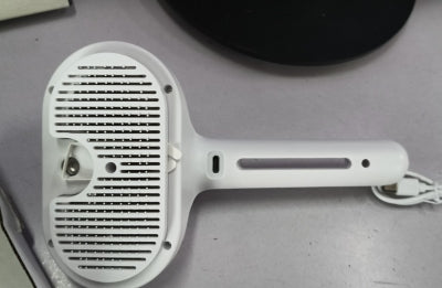Pet grooming brush misting water onto dog coat while brushing